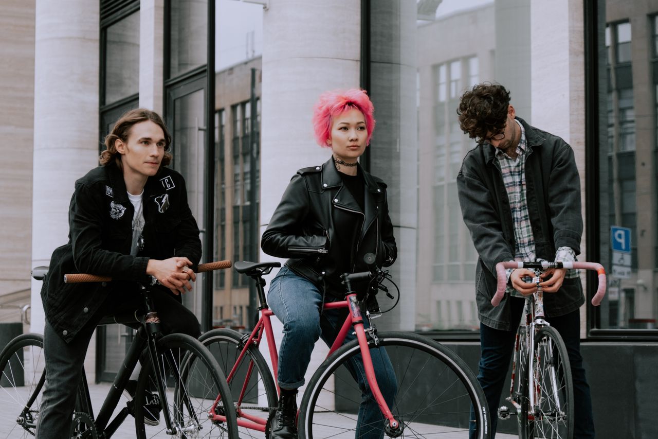 Three young adults with bikes in a stylish urban environment, showcasing fashion and recreation.