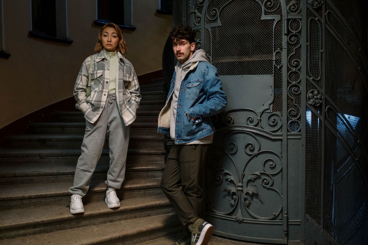 Trendy couple posing on an ornate vintage staircase in casual wear.